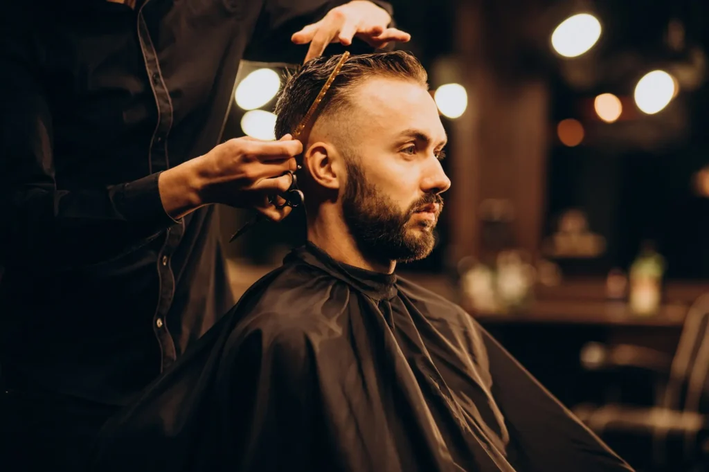 Barber strzyże męskie włosy nożyczkami i grzebieniem.
